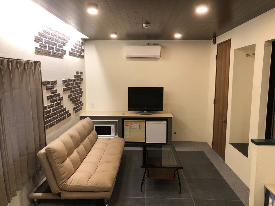 Un espacio habitable compacto con sofá, una mesita, televisor y refrigerador.