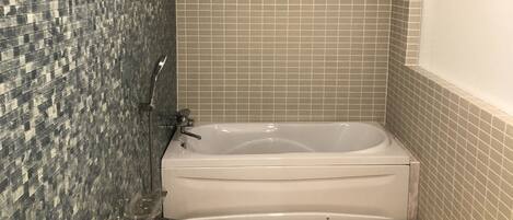 Bagno con vasca, pareti piastrellate e zona doccia.