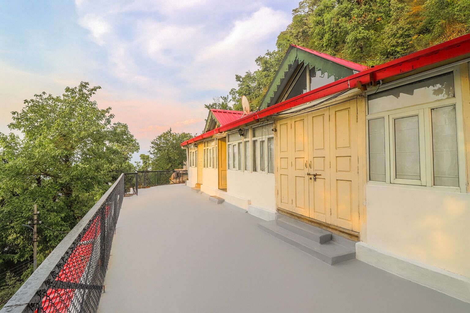 Un edificio a due piani con tetto rosso e pareti color beige, con un balcone dotato di ringhiera nera.