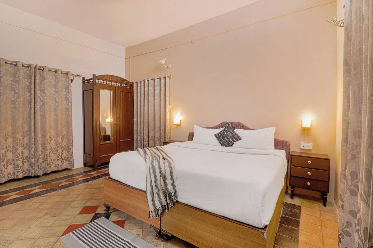 A neatly arranged bedroom with a bed, bedside tables, and curtains.