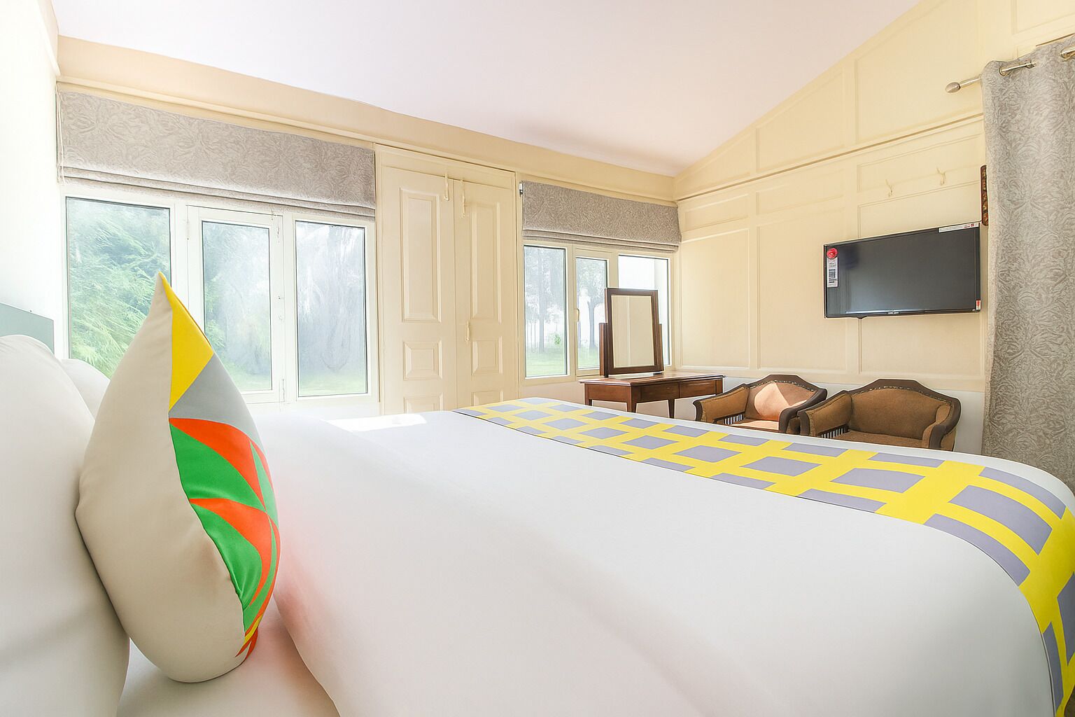 A hotel room with a large bed, a television, a desk, and a chair.