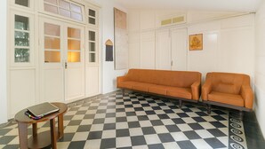 A room with a checkered floor, a sofa, a table, and a cabinet with glass doors. - The HillCrest (Dehradun)