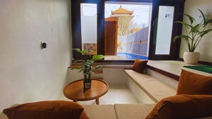 Una sala de estar moderna con un sofá, una mesita redonda y una planta en maceta.