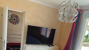 Un dormitorio con una cama, un televisor en una cómoda, un armario y una ventana con cortinas.
