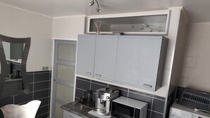 Una cocina moderna con armarios grises, una cafetera y una lavadora.
