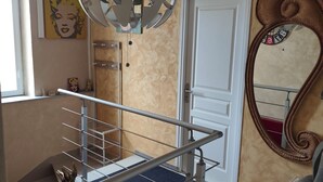 Una escalera con barandilla de metal, un candelabro y un espejo en la pared.