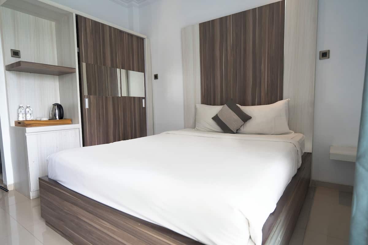 Une chambre moderne avec un grand lit, une tête de lit en bois et une armoire intégrée.