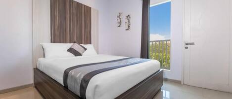 A bedroom with a bed, a wooden headboard, a window with a view, and a door.