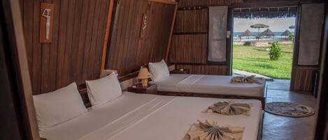 A room with two beds, wooden walls, and a view of the beach.