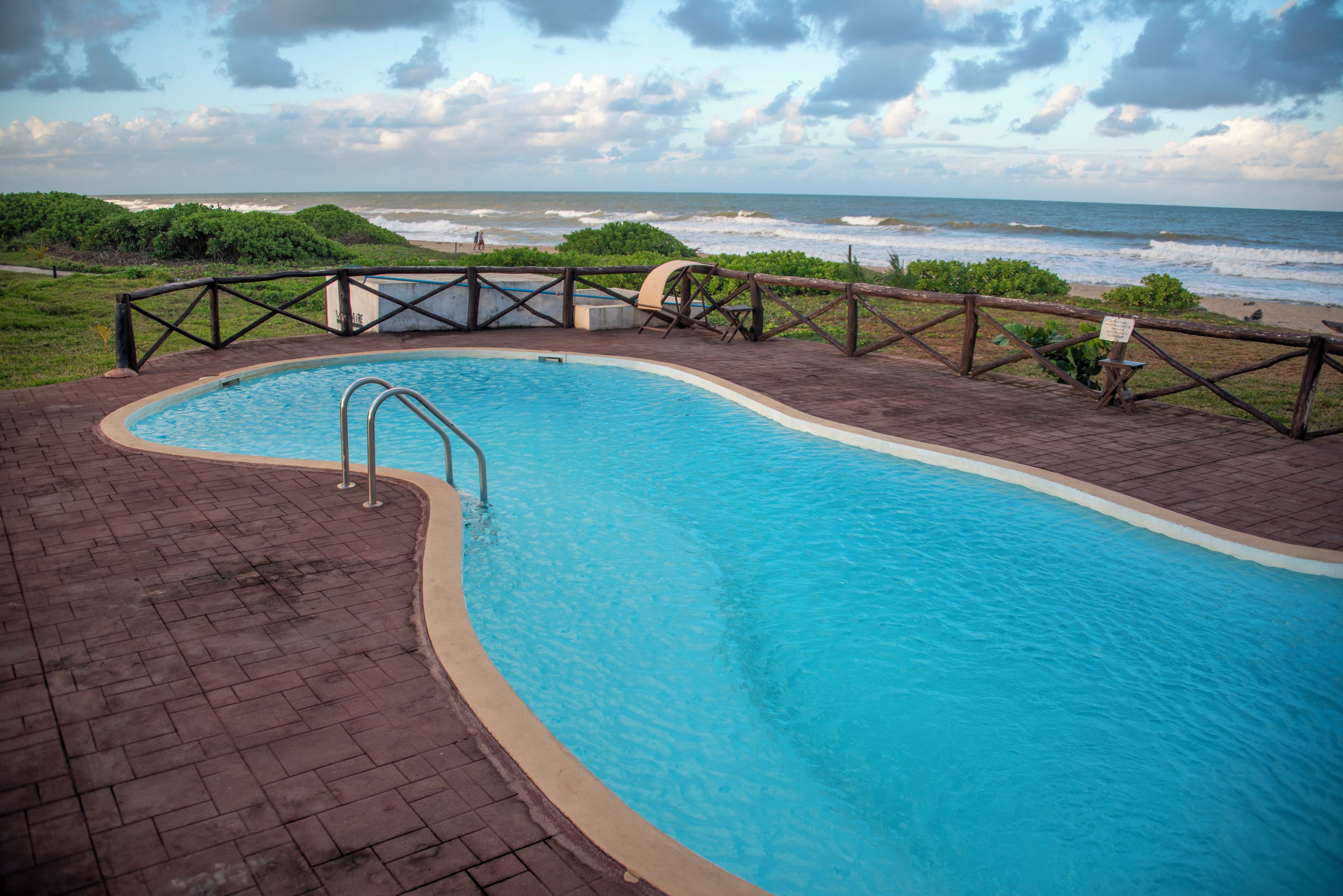 Una piscina con cubierta de madera y vista al océano.