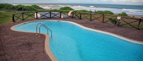 Una piscina con cubierta de madera y vista al océano.