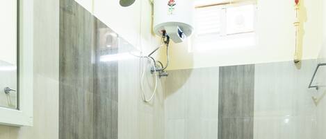 A bathroom with two toilets, a sink, a shower, and a water heater.