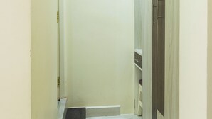 A narrow hallway with a wooden wardrobe, a white door, and a small step leading to a landing. - Shrees Hotel (Perundurai)