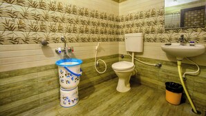 A bathroom with a toilet, sink, and a trash bin. - Hotel BS International Mysore (Mysore)
