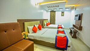 A hotel room with a large bed, a smaller bed, a sofa, a TV, and a desk. - Hotel BS International Mysore (Mysore)