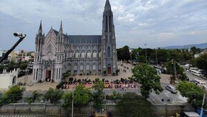 A large Gothic-style cathedral with a prominent spire, a spacious courtyard, and a busy street in the foreground. - Hotel BS International Mysore (Mysore)