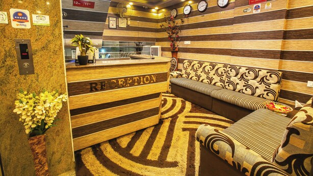 A reception area with a wooden reception desk, a sofa, a clock, and a 'No Smoking' sign. - Hotel BS International Mysore (Mysore)
