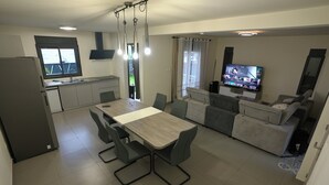 Una cocina moderna con comedor, televisor y sofá.