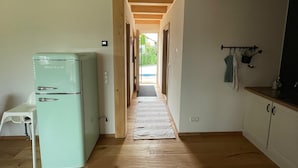 A kitchen with a vintage refrigerator, wooden flooring, and a view through an open door. - Apartment 'dahoimelig' with mountain view, private terrace and Wi-Fi (Friesenried)