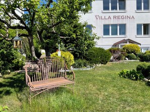 A bench in a garden area with a building labeled 'Villa Regina' in the background.