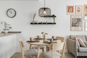 A modern dining area with a round table, chairs, a wall clock, and a pendant light.
