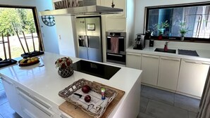 A modern kitchen with a large island, built-in appliances, and a view of the outdoors. - Villa des chateaux du pessac leognan (Martillac)