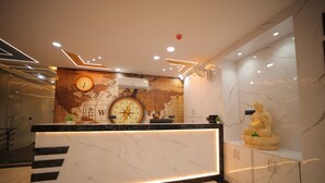 A reception desk with a world map and a clock, a marble floor, and a statue on a shelf.
