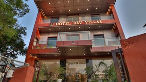 A hotel with a modern design, featuring a prominent entrance with steps and potted plants.