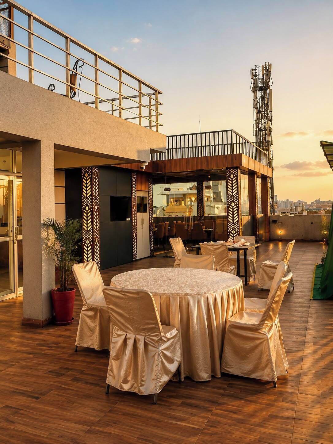 An outdoor dining area with round tables and chairs, a potted plant, and a view of the city skyline.