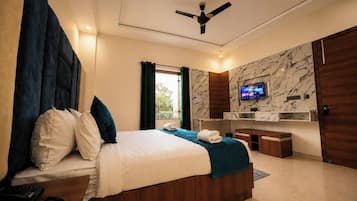 A modern hotel room with a bed, a desk, a television, and a ceiling fan.