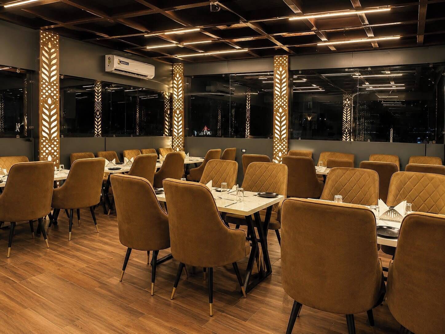 Een restaurantinterieur met houten vloeren, comfortabele stoelen en gedekte tafels.