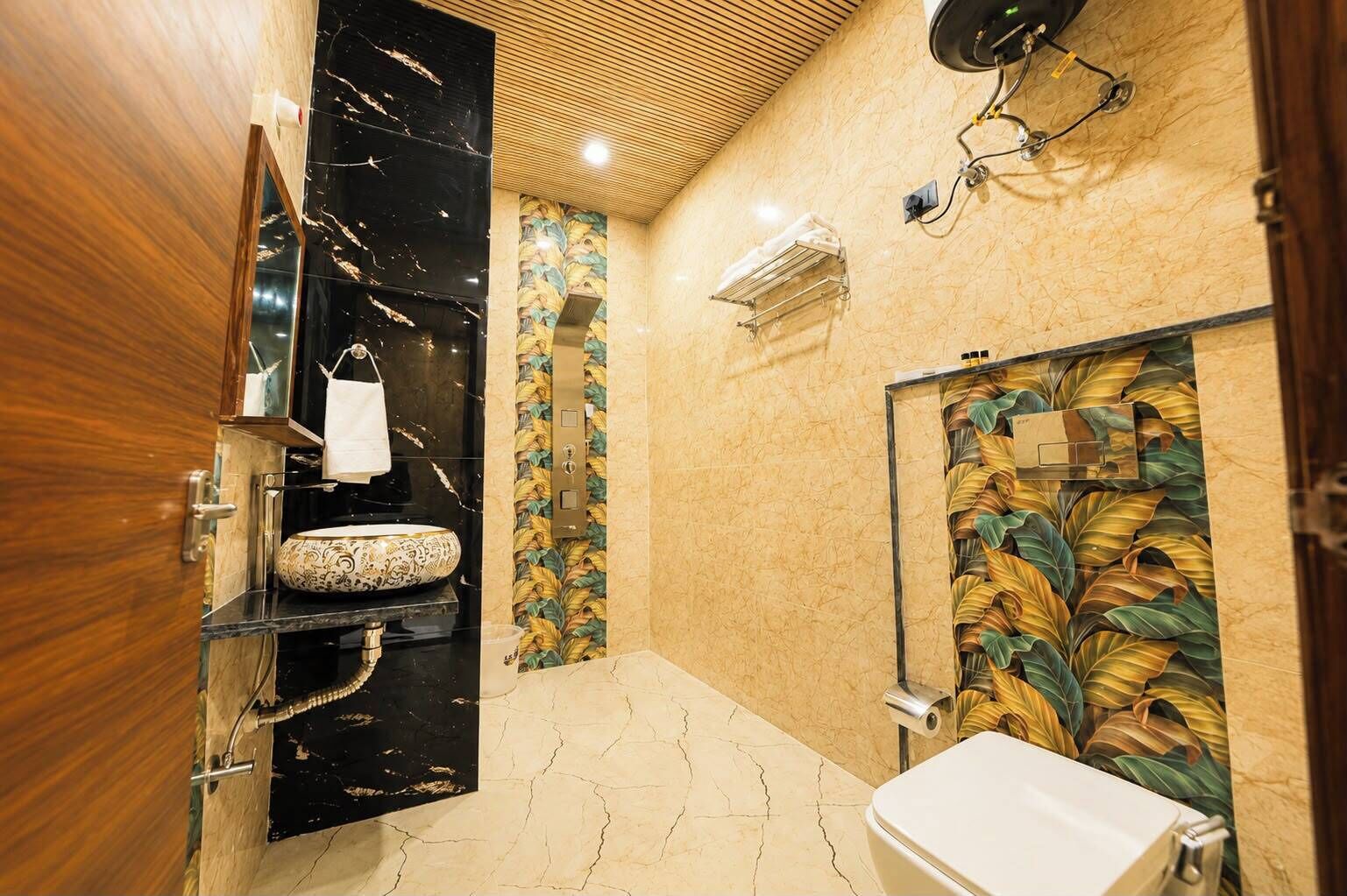 A bathroom with a marble sink, a toilet, a shower with a leaf-patterned wall, and a wooden door.