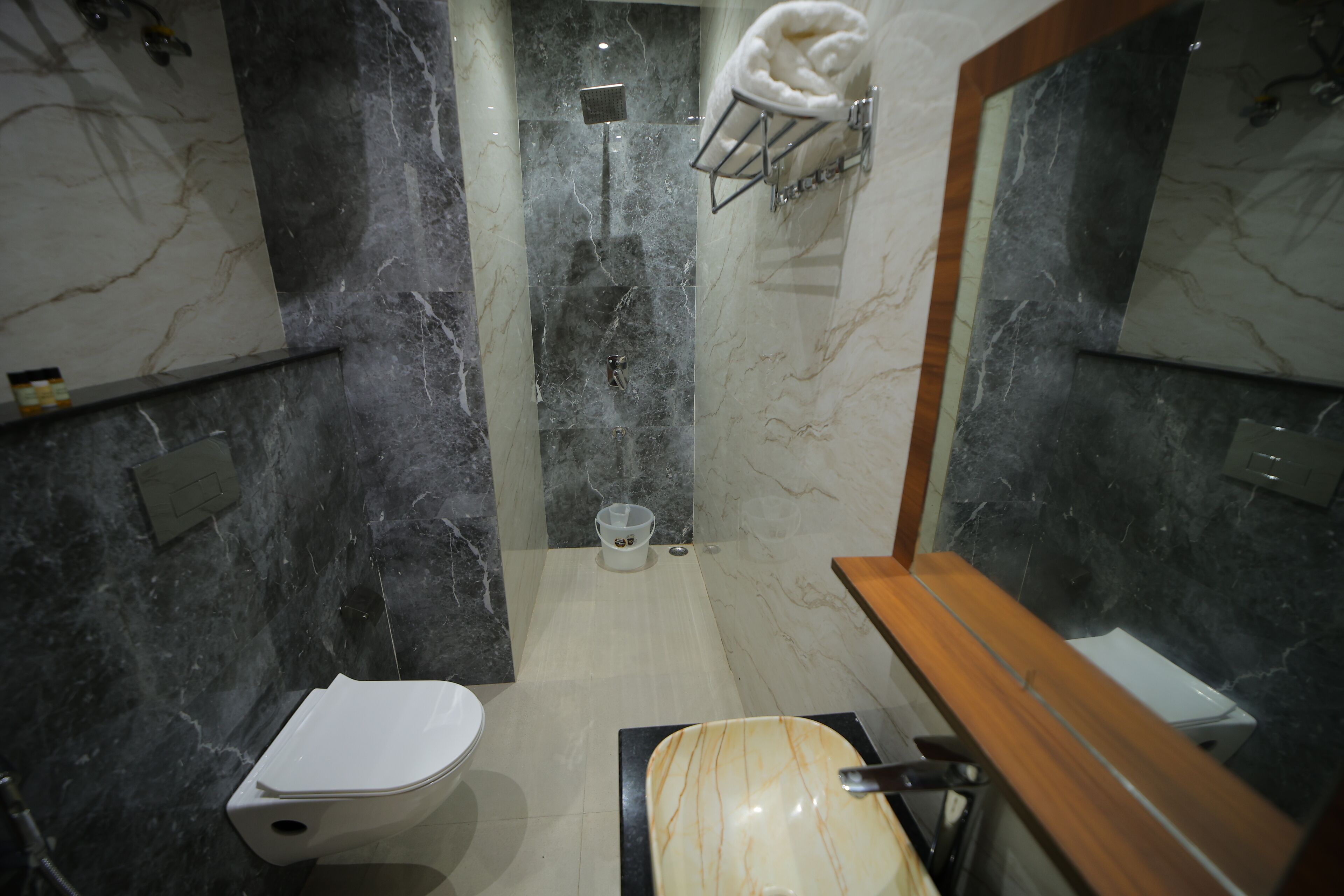 A modern bathroom with a marble shower, a toilet, and a sink.