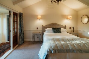 A bedroom with a bed, two bedside tables, a nightstand, a mirror, and a door leading to another room.