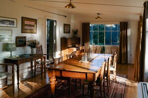 Une salle à manger avec une table en bois, des chaises et une fenêtre avec des rideaux.