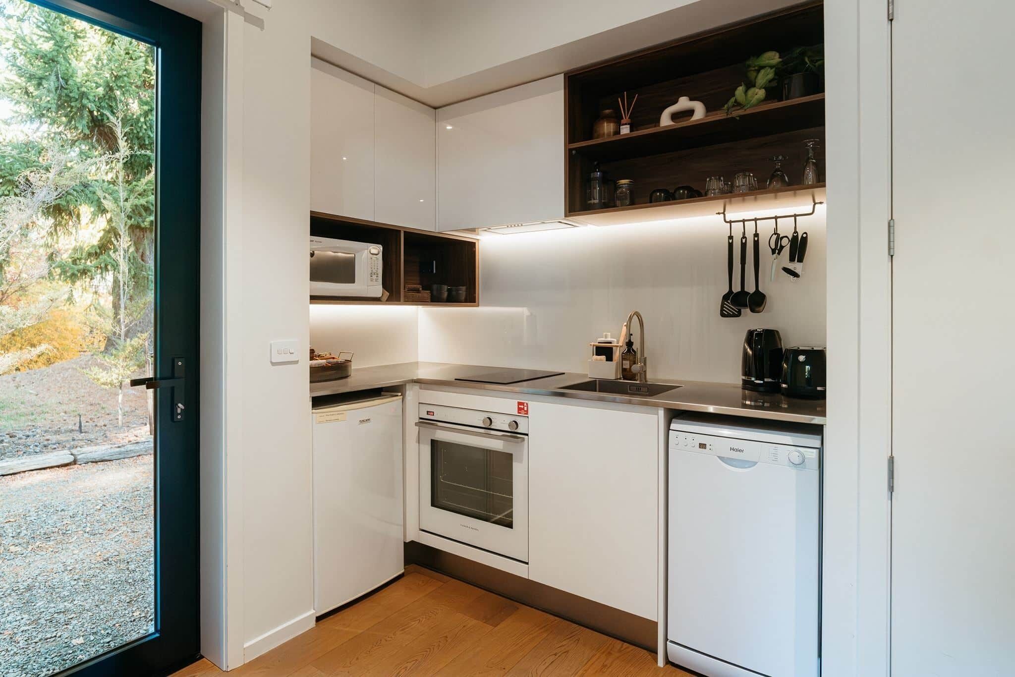 Cocina compacta equipada con microondas, horno, lavavajillas y una pequeña encimera.