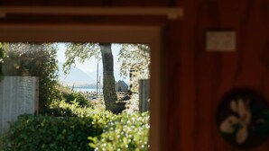 A view through a window with a mountain in the background, a tree, and a building. - Awa Cottage - Lake Tekapo (Lake Tekapo)