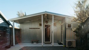 A metal building with a covered porch, a deer head decoration, and an air conditioning unit. - Awa Cottage - Lake Tekapo (Lake Tekapo)