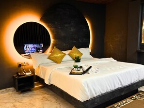 Une chambre moderne avec un grand lit, un miroir rond et un téléviseur fixé au mur.