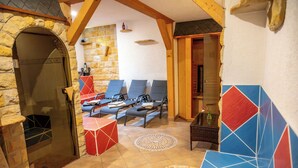 A stone-walled room with a fireplace, a seating area with lounge chairs, and a small table with a vase. - AaRa Hotel (Radeberg)
