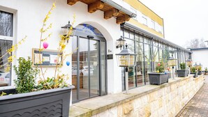 A hotel with a white facade, large windows, and outdoor potted plants. - AaRa Hotel (Radeberg)