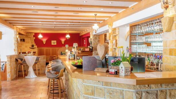 A bar area with stone walls, wooden beams, and a variety of bar tools and bottles. - AaRa Hotel (Radeberg)