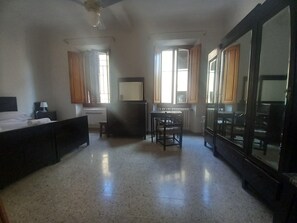 A hotel room with a bed, a desk, a chair, a wardrobe, and a large mirror. - Sant Orsola Apartament (Florence)