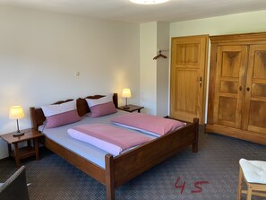 A bedroom with a wooden bed, two bedside tables with lamps, a wardrobe, and a small chair.