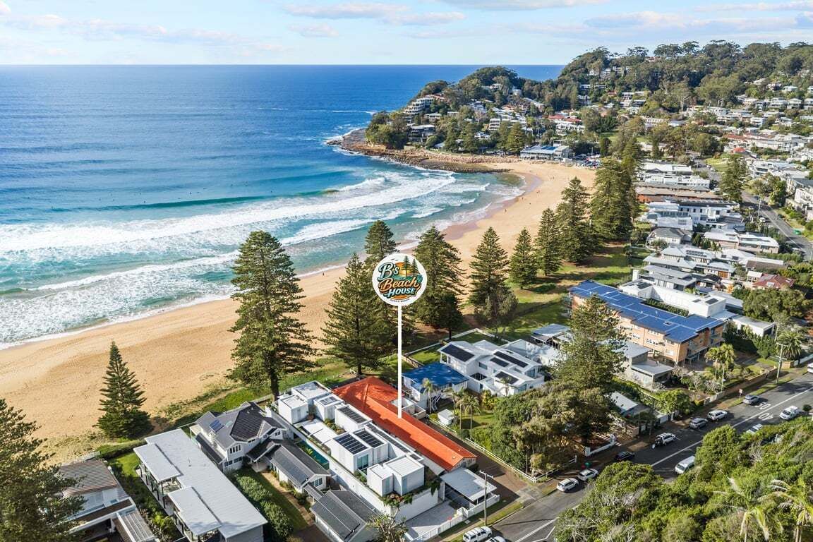 Un quartier résidentiel situé sur la côte, avec une plage, des maisons et un panneau indiquant « Beach House ».