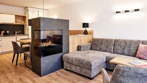Una sala de estar moderna con un sofá gris, una mesita de madera y una chimenea empotrada.