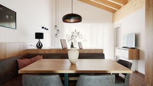 Un comedor moderno con una mesa de madera, sillas tapizadas de color gris, un florero blanco con flores y una lámpara colgante.