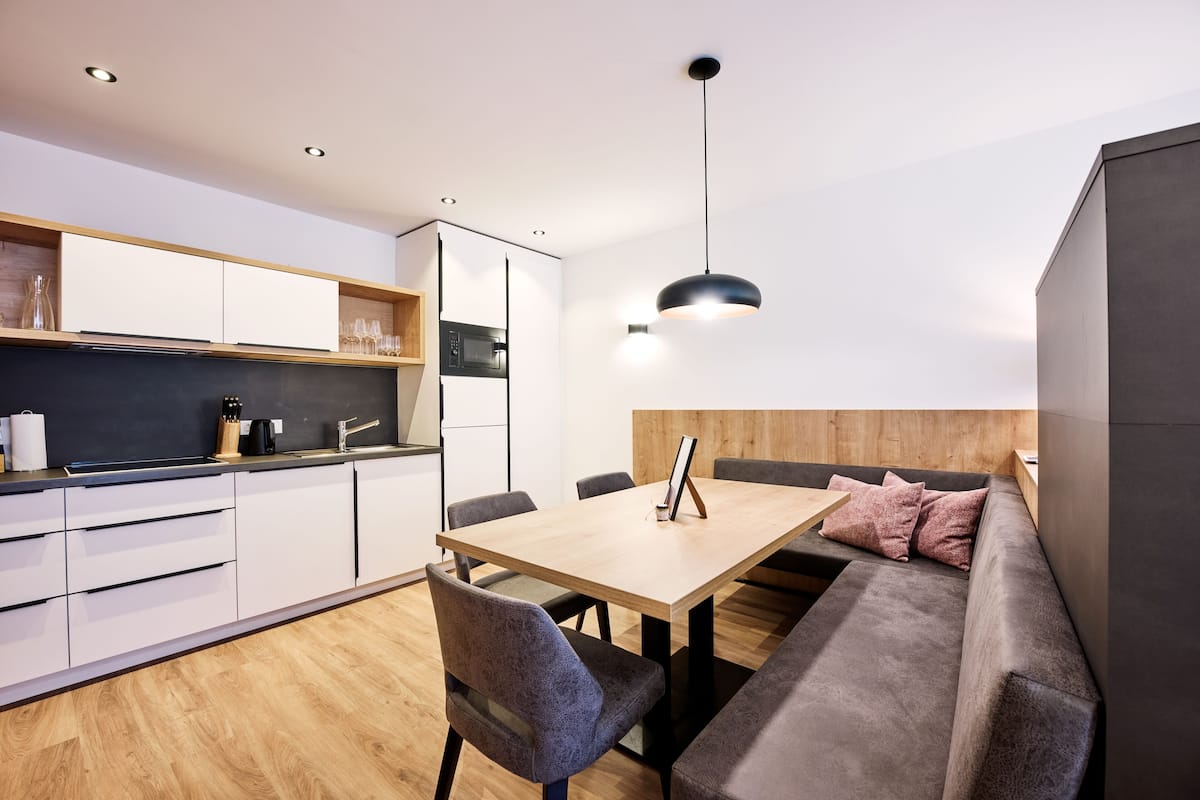 A modern kitchen with white cabinets, a wooden countertop, and a black pendant light.