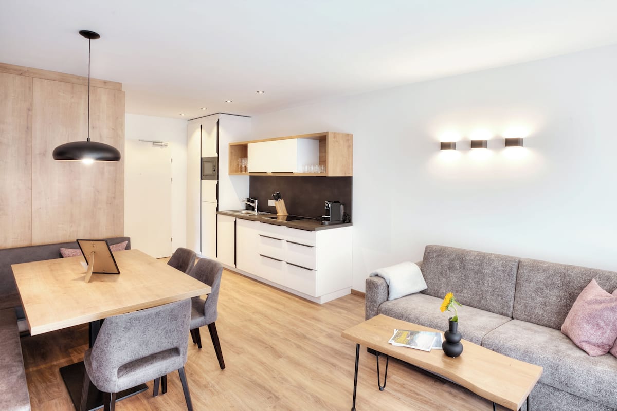 A modern living space with a dining area, kitchenette, and a sofa.
