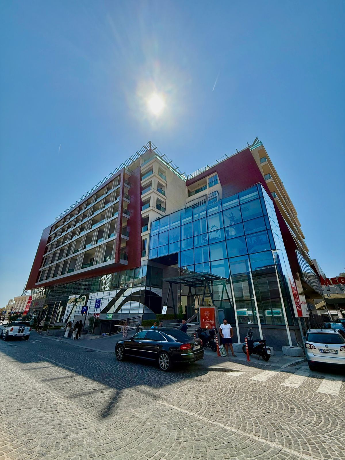 A modern hotel with a glass facade, multiple floors, and a prominent entrance.